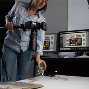 Een afbeelding waarop de Calibrite ColorChecker Classic Mini wordt gebruikt bij een macrofotoshoot van verschillende postzegels. De kleurreferentiekaart kan door fotografen worden gebruikt om te voorspellen en te controleren hoe kleuren eruit zullen zien onder verschillende lichtomstandigheden, en om een nauwkeurige kleurweergave tijdens het bewerken te waarborgen. Het toont 24 vierkanten, elk met een kleurreferentie.